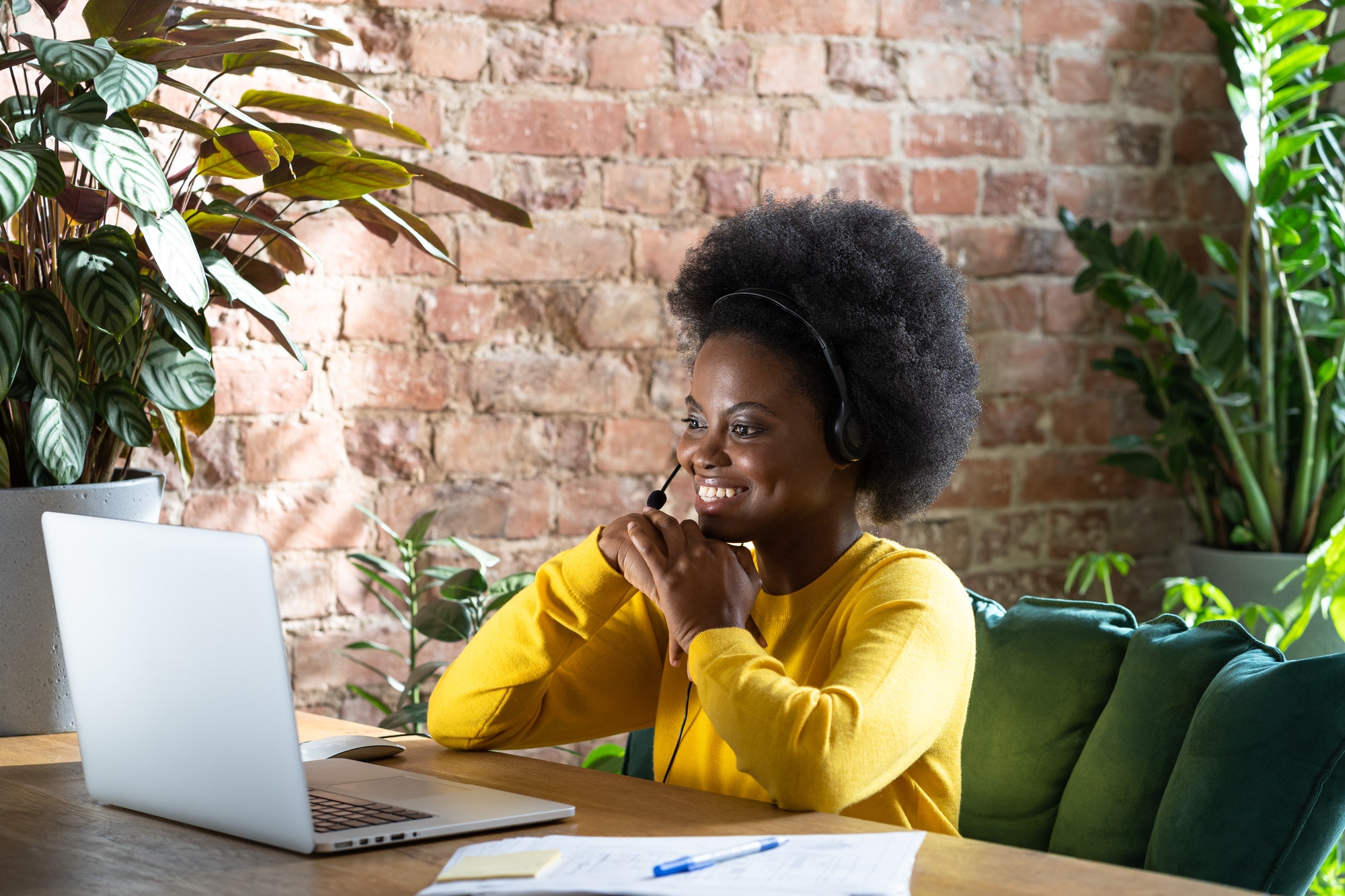 Afro-American biracial millennial woman wearing headset, talking in zoom app, watching webinar